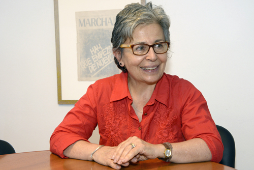 Pilar Barreiro sentada con manos en el escritorio, mirando hacia la izquierda 